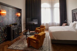 Ένα δωμάτιο ξενοδοχείου με ένα μεγάλο κρεβάτι, δύο πολυθρόνες, ένα μικρό τραπέζι, μια τηλεόραση και έναν διακοσμητικό τοίχο με τζάκι.