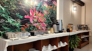 A buffet setup with a coffee station, tea service, and a decorative wall with flowers. - Aura Hotel (Chiclayo)