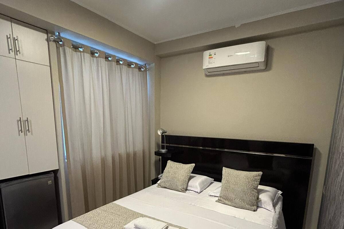 Une chambre d’hôtel équipée d’un lit, d’une armoire, d’un climatiseur et d’une fenêtre avec des rideaux.