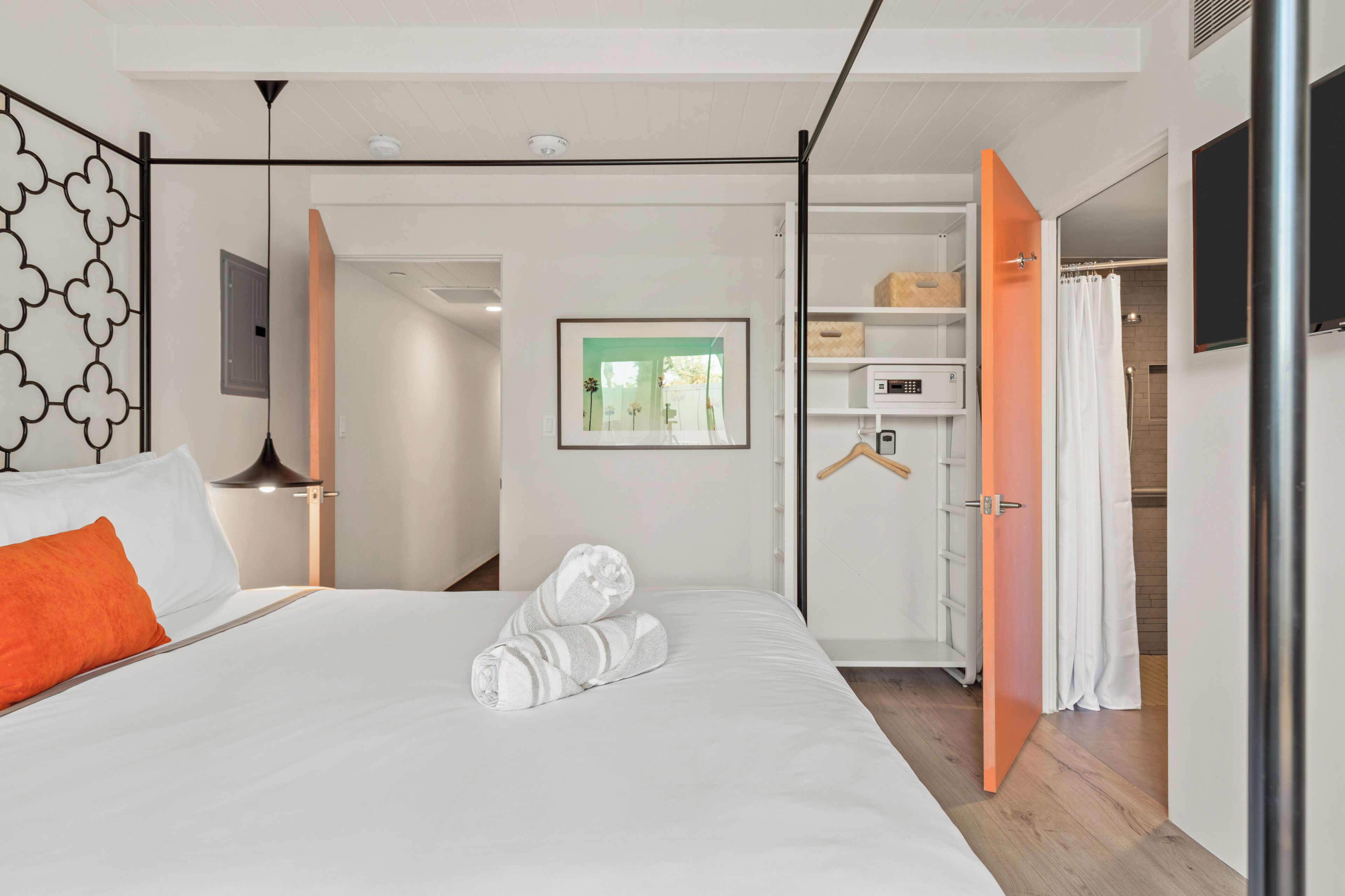 Ein modernes Hotelzimmer mit Bett, Schrank, Spiegel und einem Bild an der Wand.