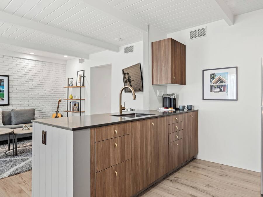 A modern kitchen with a central island, wooden cabinets, and stainless steel appliances.
