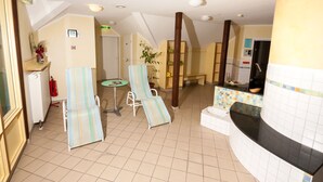 Een hotel lobby met een receptiebalie, twee gestreepte lounge fauteuils, een tafeltje met een vaas, en een brandblusser.