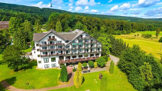 Een meerlaags hotel met een centrale binnentuin, omgeven door weelderige begroeiing en een golfbaan.