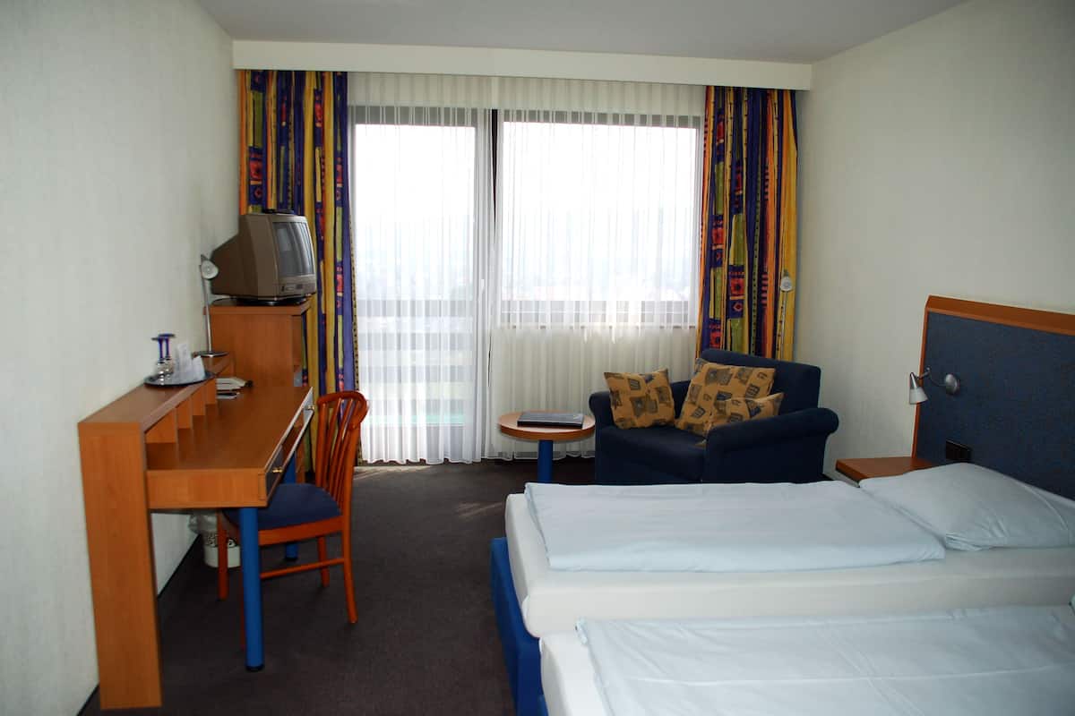 Une chambre d’hôtel comprenant un lit, un bureau avec une télévision, une chaise et un canapé.