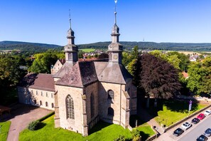 A historic church with two prominent towers, a well-maintained lawn, and a parking area. - Hotel der Jägerhof (Willebadessen)