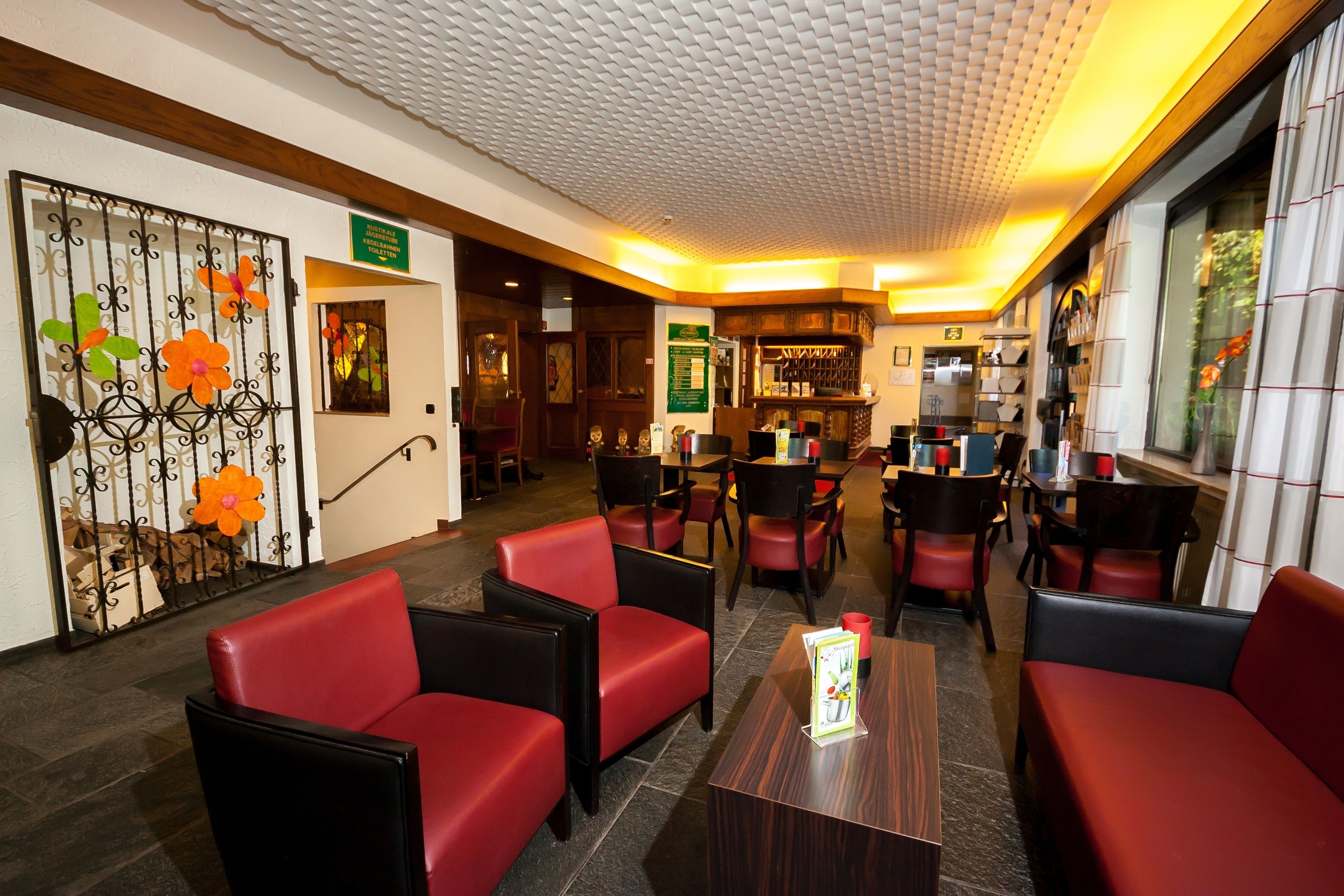 A lobby with red and black seating, a reception desk, and a patterned ceiling.
