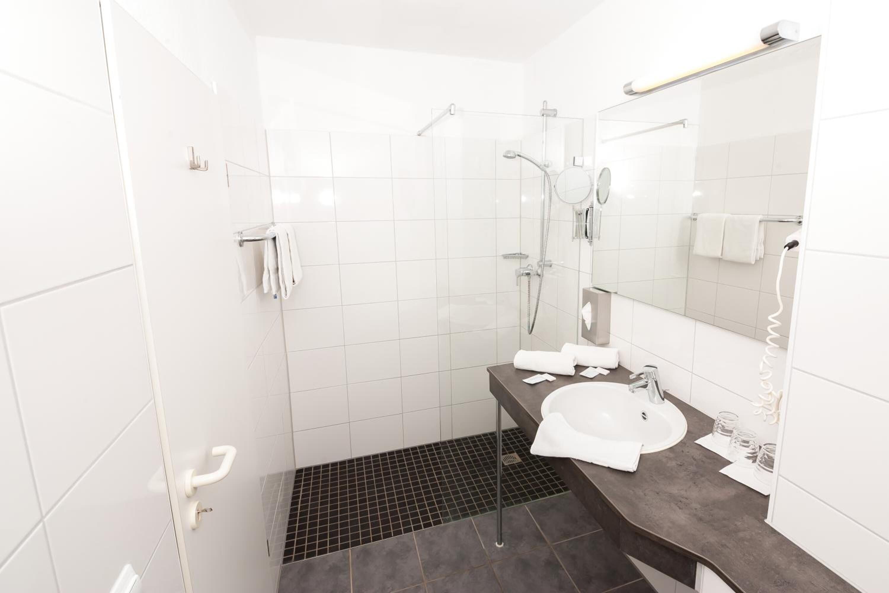 Un baño moderno con ducha, lavabo y espejo.