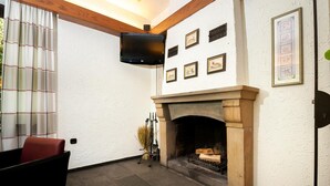 Een kamer met een open haard, een wandtelevisie en beeldeframes aan de muur.