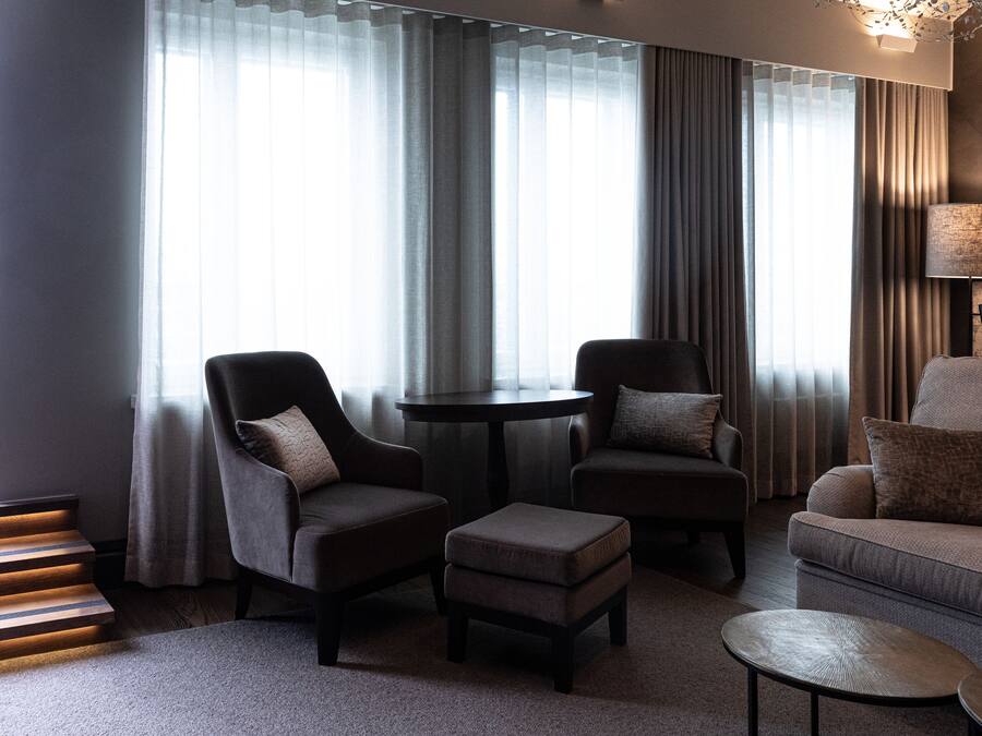 Una sala de estar moderna con dos sillones, un sofá, una mesita redonda y una lámpara.