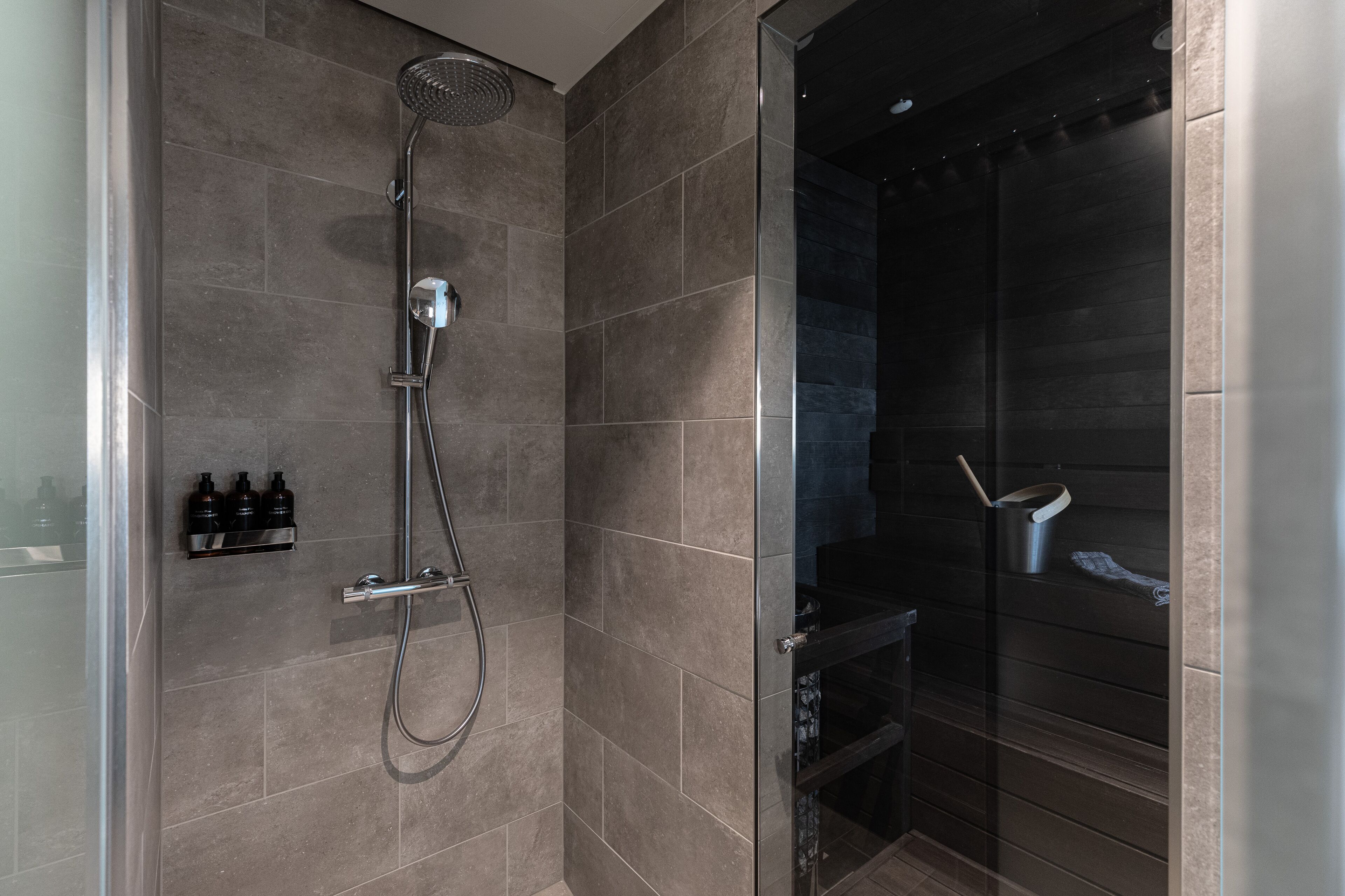 A modern shower area with a glass enclosure, a handheld showerhead, and a wall-mounted control panel.