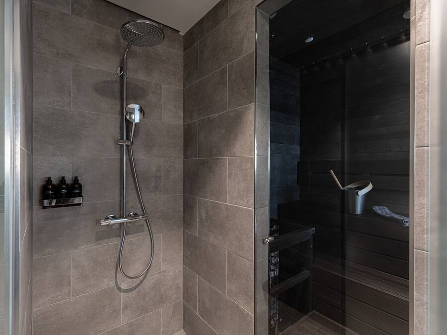 A modern shower area with a glass enclosure, a handheld showerhead, and a wall-mounted control panel.