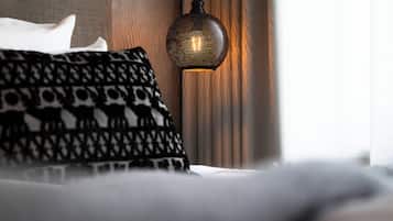 Una cama con almohadones estampados y una lámpara de pared con textura.