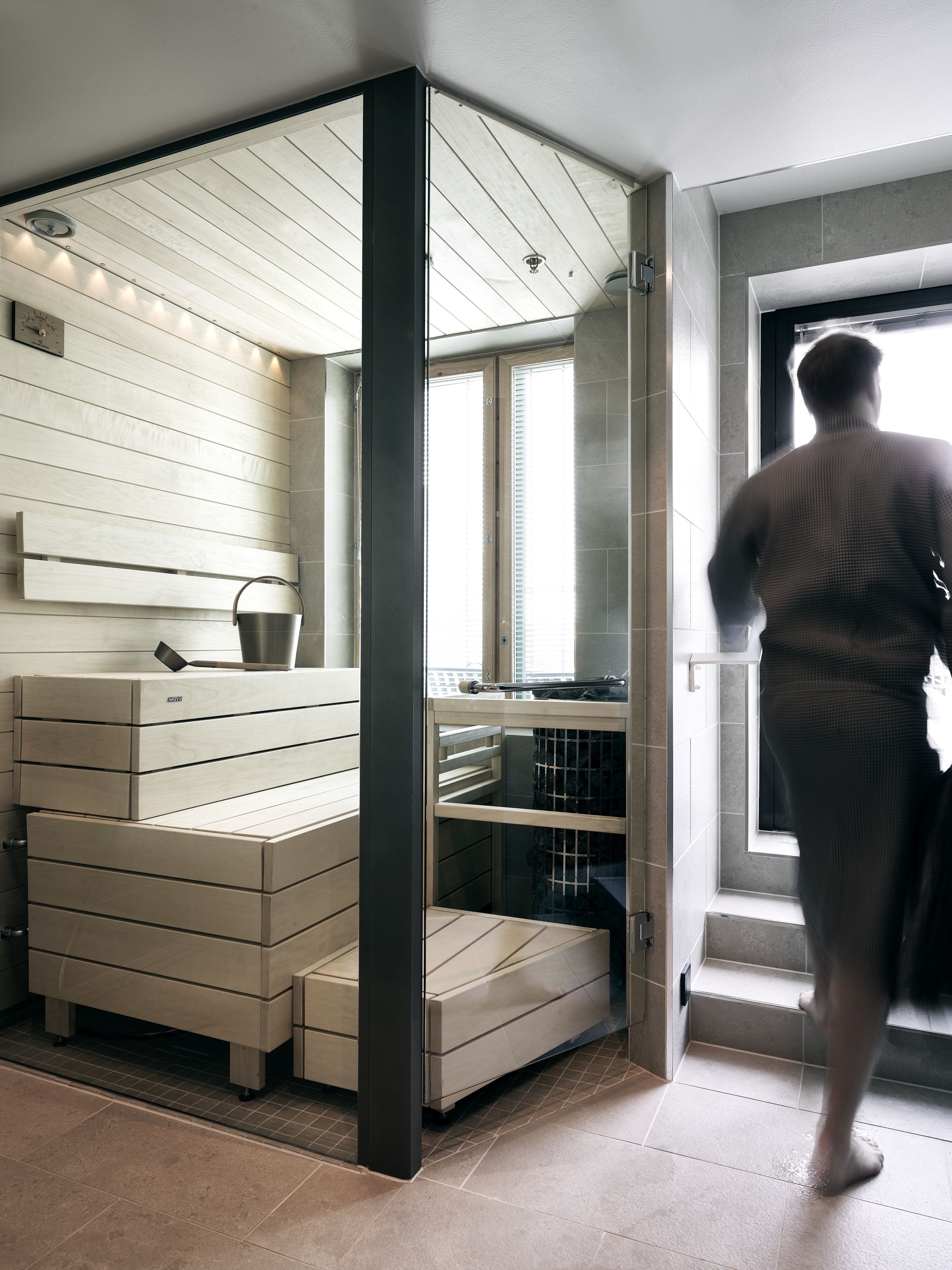 Quarto moderno com sauna integrada, uma janela ampla e vista para a cidade.