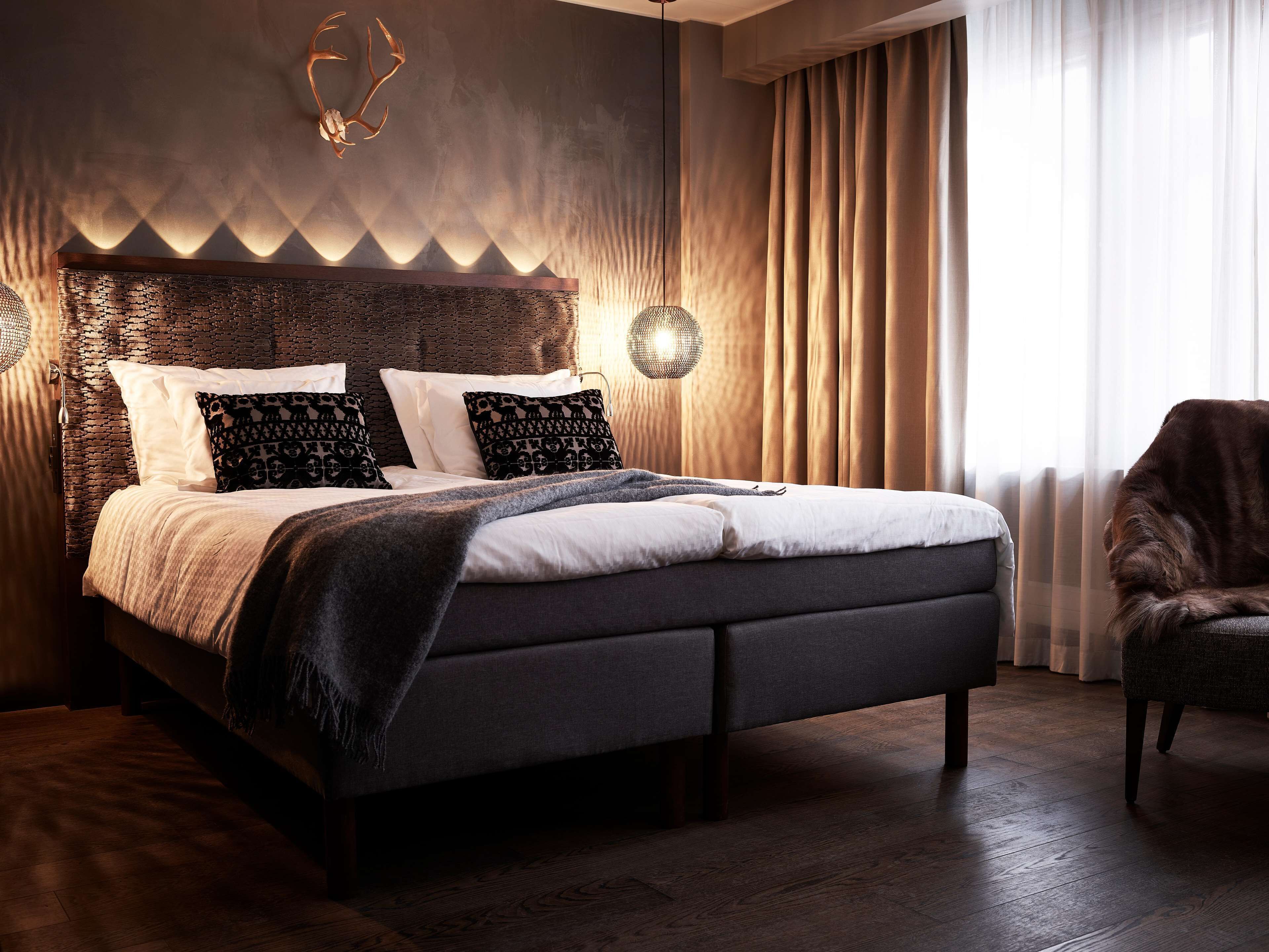 Un dormitorio moderno con una cama grande, cabecero de madera oscura y un adorno en la pared.