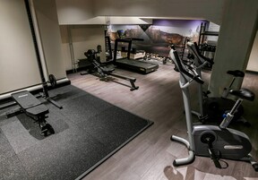 Una palestra con tapis roulant, panche per pesi e diverse macchine per esercizi.