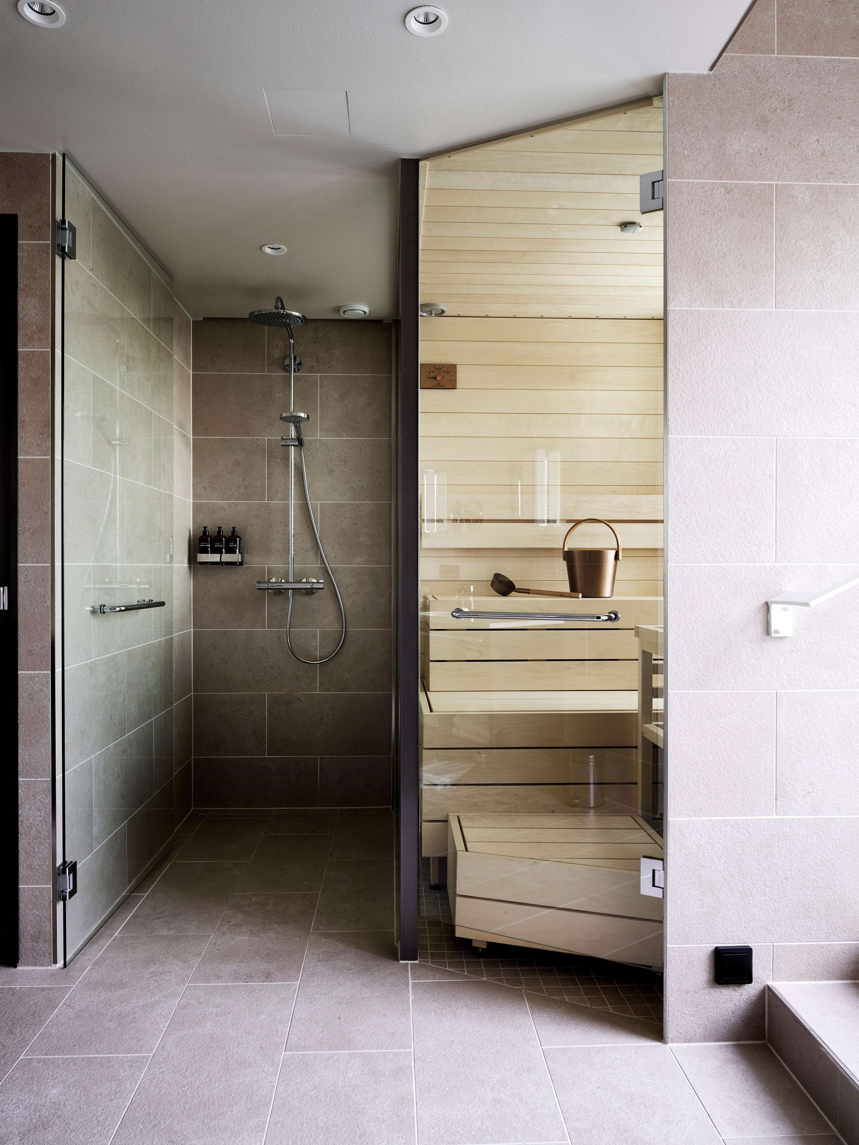 A modern bathroom with a glass shower enclosure, a wooden vanity, and a built-in shelf.