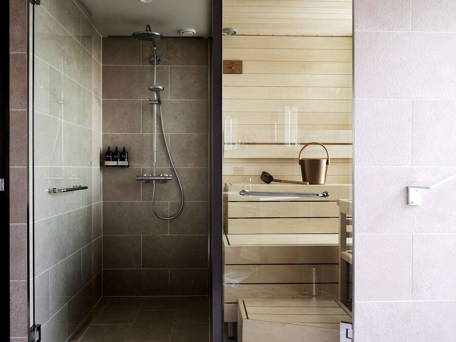 A modern bathroom with a glass shower enclosure, a wooden vanity, and a built-in shelf.