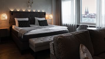 Habitación de hotel moderna con una cama grande, un sofá, vistas a la ciudad y una pared decorativa con cuernos.