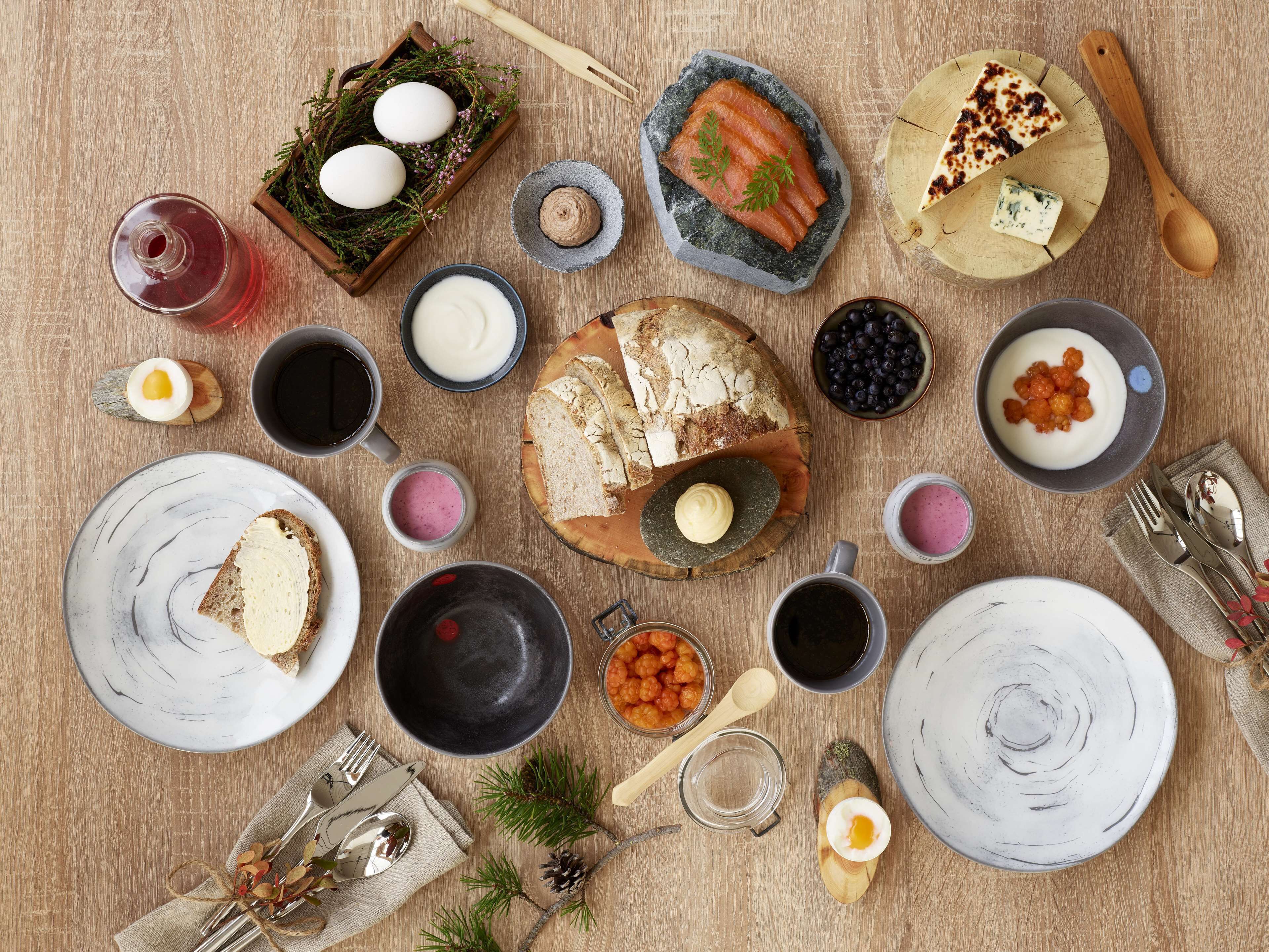 A table set with various foods, including bread, eggs, and berries, suggesting a breakfast or brunch setting.