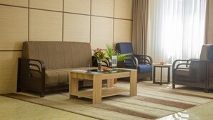 Uma sala de estar moderna com um sofá, duas poltronas, uma mesa de centro e uma mesinha lateral.
