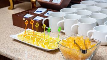 A buffet setup with a plate of sliced oranges and a bowl of sugar cubes.