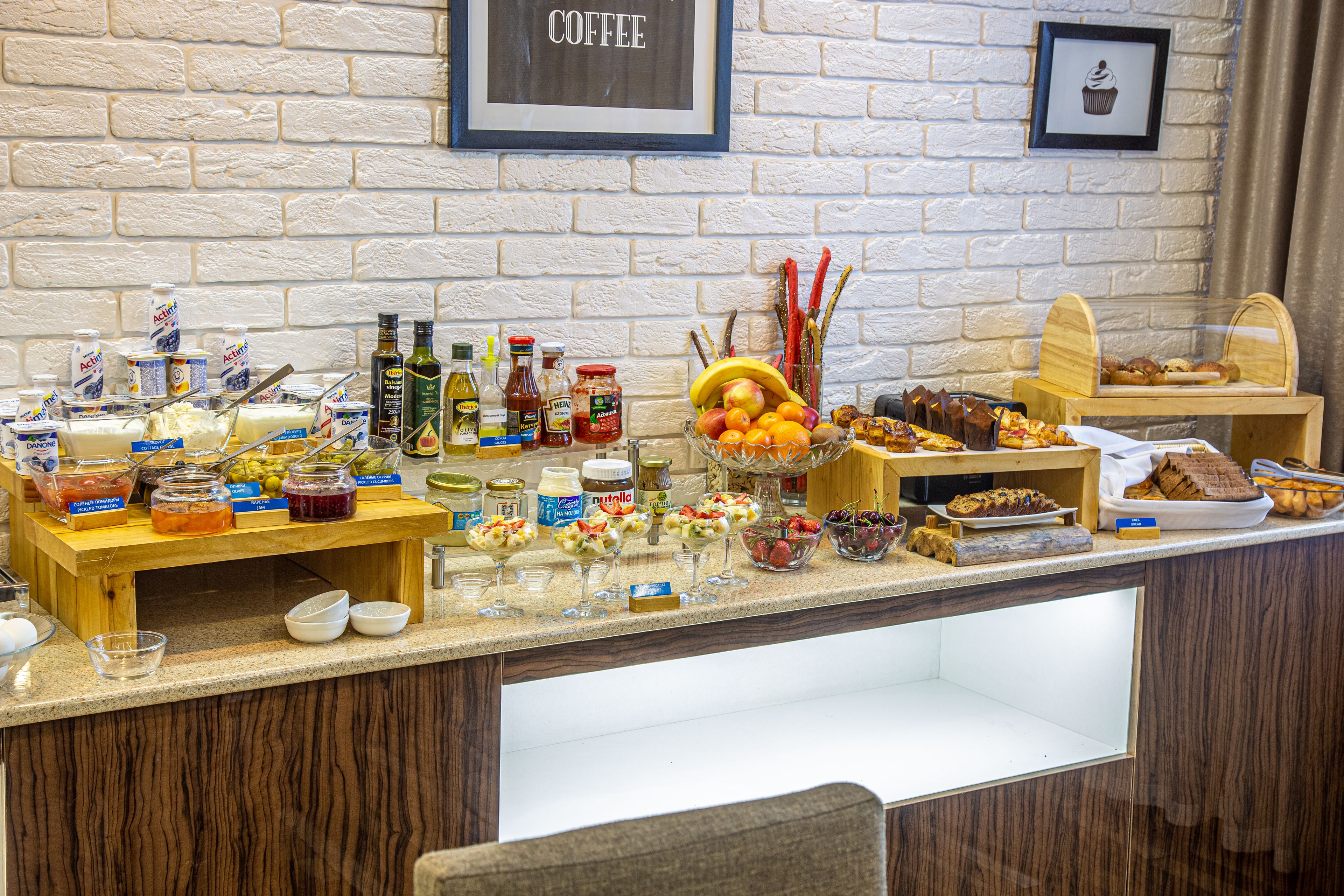 Mostrador de buffet con diferentes alimentos, salsas y un letrero de café en la pared.