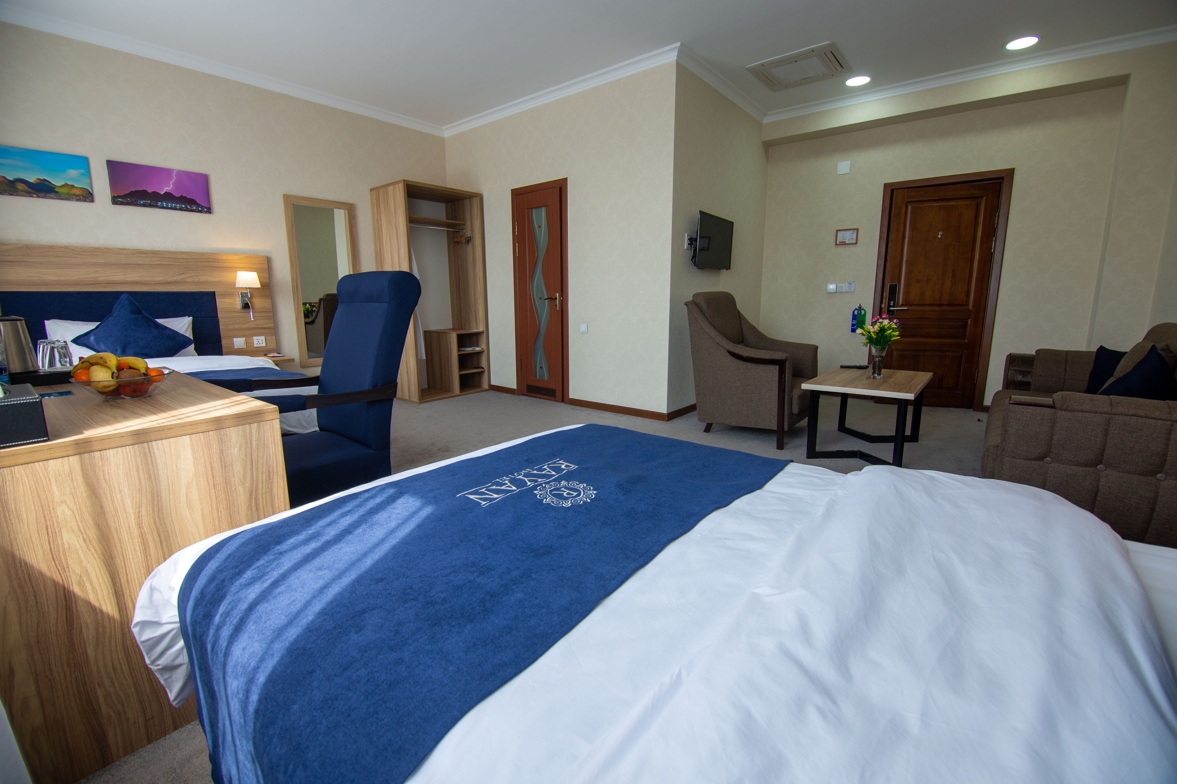 A hotel room with a bed, a desk, a chair, a small table, and a sofa.