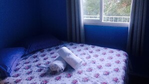 Ein Schlafzimmer mit Bett, Fenster und Vorhängen.