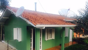 Ein grünes Haus mit Ziegeldach, Satellitenschüsseln und einer kleinen Veranda.