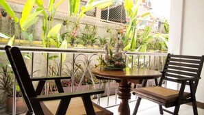 Un balcon avec deux chaises, une table et diverses plantes en pot.