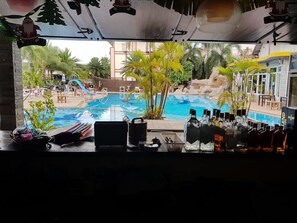 Un espace bar avec vue sur la piscine, du matériel de bar et des sièges en plein air.