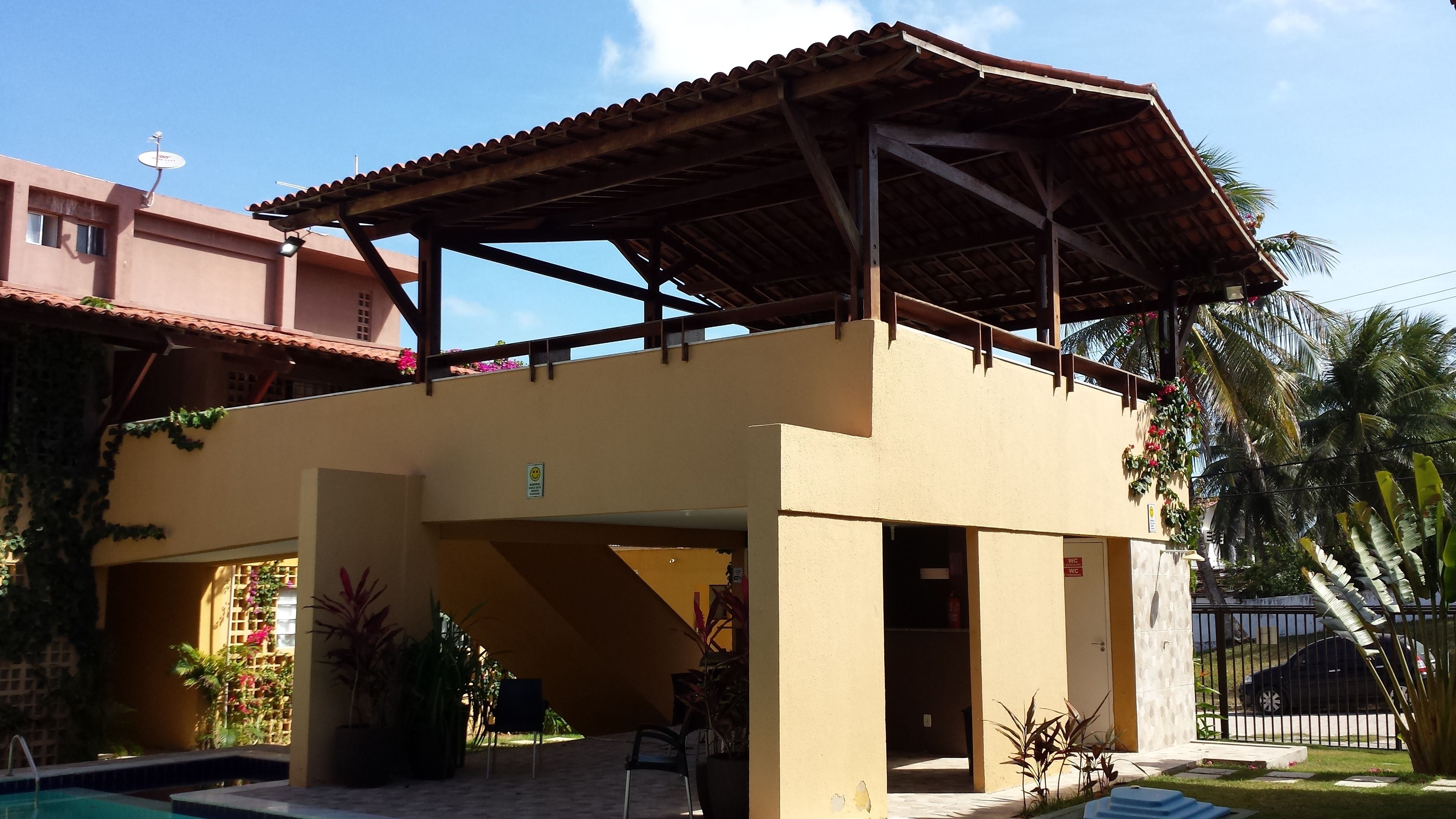 A two-story building with a covered patio area, a swimming pool, and potted plants.