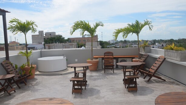 A rooftop terrace with wooden furniture, potted plants, and a view of the cityscape. - Studios Siena Av CTM, colonia Zazil Ha (Playa del Carmen)