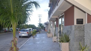 A street view with a building featuring a stone facade, a parked car, and a palm tree. - Studios Siena Av CTM, colonia Zazil Ha (Playa del Carmen)