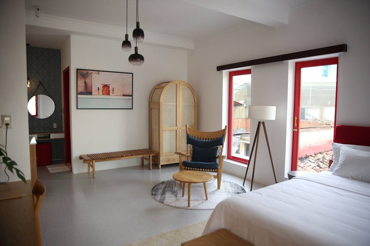 Una habitación de hotel moderna con una cama, una mesa redonda, una silla, un espejo y un cuadro en la pared.