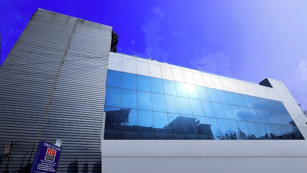 A modern hotel building with a reflective glass facade and a prominent 'First Floor' sign. - Hotel Elite Continental - Airport Road Andheri (Mumbai)