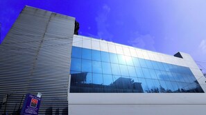 A modern hotel building with a reflective glass facade and a prominent 'First Floor' sign.