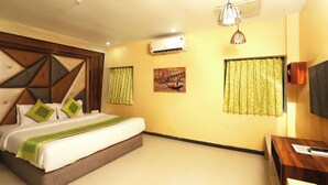 A hotel room with a large bed, a desk, an air conditioning unit, and a painting on the wall. - Hotel Elite Continental - Airport Road Andheri (Mumbai)