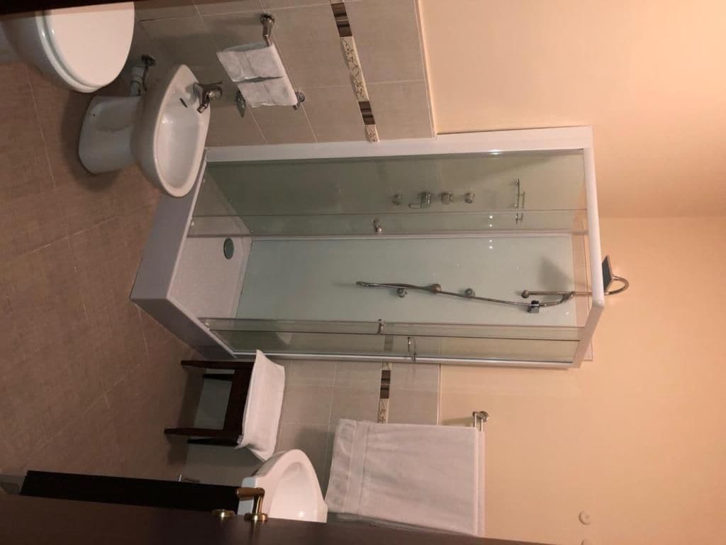 Un baño con bañera acristalada, inodoro y lavabo.
