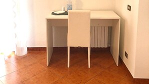 A small, white, corner desk with a chair, two starfish wall decorations, a water bottle, and a cup on the desk. - I Faraglioni (Terrasini)