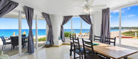 Un comedor con vista a la playa, ventanas amplias y un ventilador de techo.