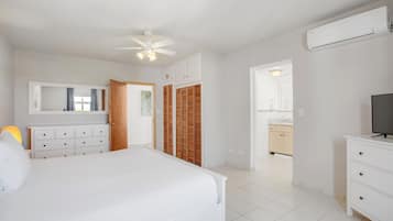 A bedroom with a bed, a dresser, a TV, and a ceiling fan.