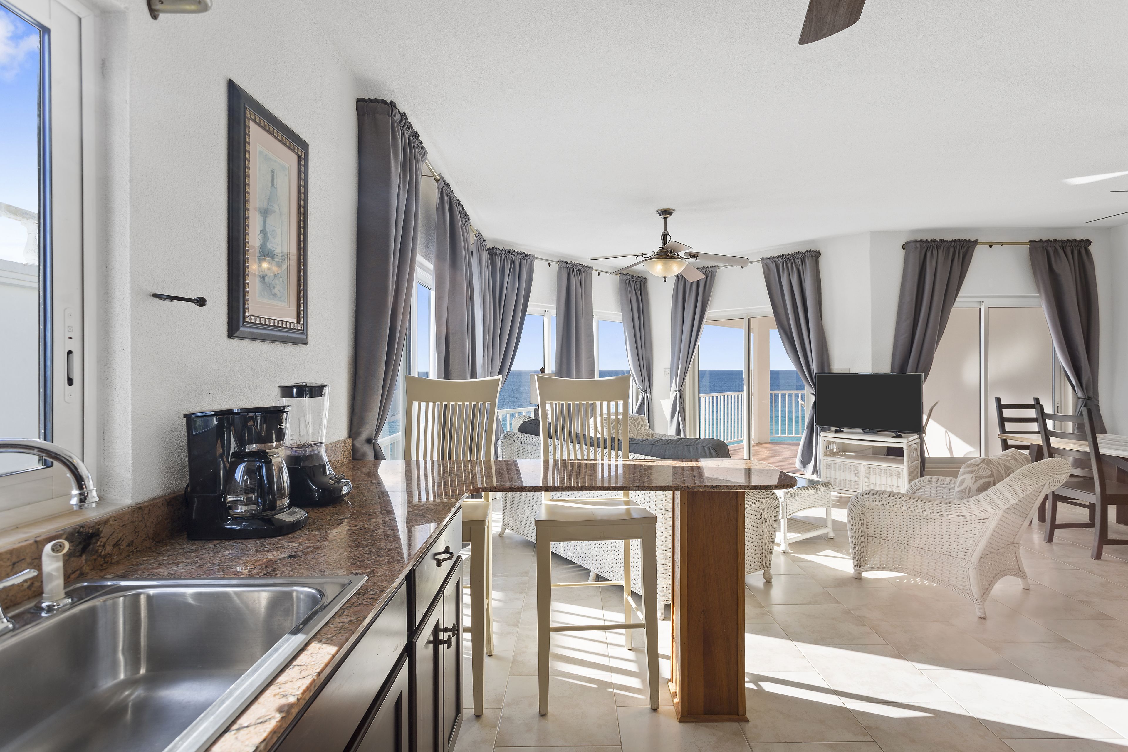 A modern kitchen with a sink, a coffee maker, and a dining area with a table and chairs.