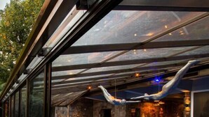 A modern indoor pool area with a glass enclosure, a wooden deck, and a lounge chair. - Wood Hotel Gramado (Gramado)