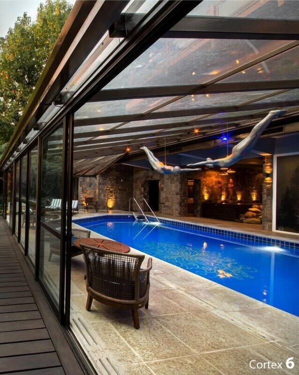 A modern indoor pool area with a glass enclosure, a wooden deck, and a lounge chair. - Wood Hotel Gramado (Gramado)