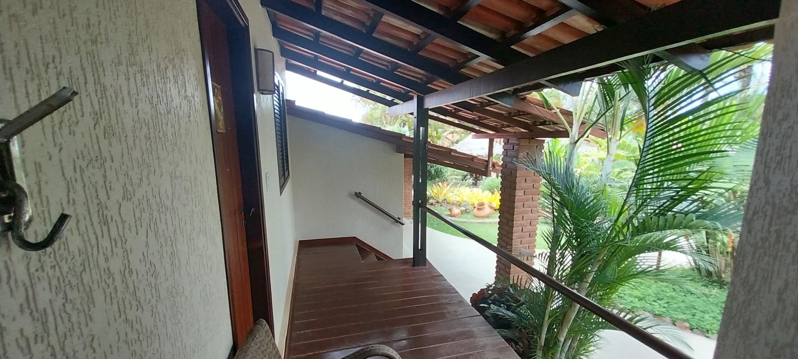 A wooden staircase leading to a covered outdoor area with a view of a garden.