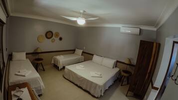 A hotel room with two single beds, a desk, a chair, a ceiling fan, and a wall-mounted air conditioner.