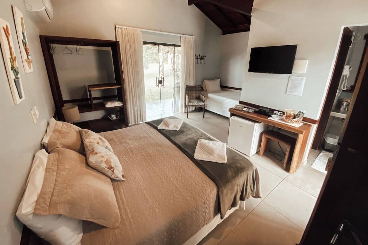 A bedroom with a bed, a desk, a chair, and a TV.