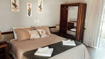 A hotel room with a large bed, a wooden wardrobe, and three wall-mounted artworks.