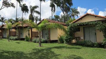 A row of single-story buildings with a tiled roof, surrounded by well-maintained grass and palm trees.